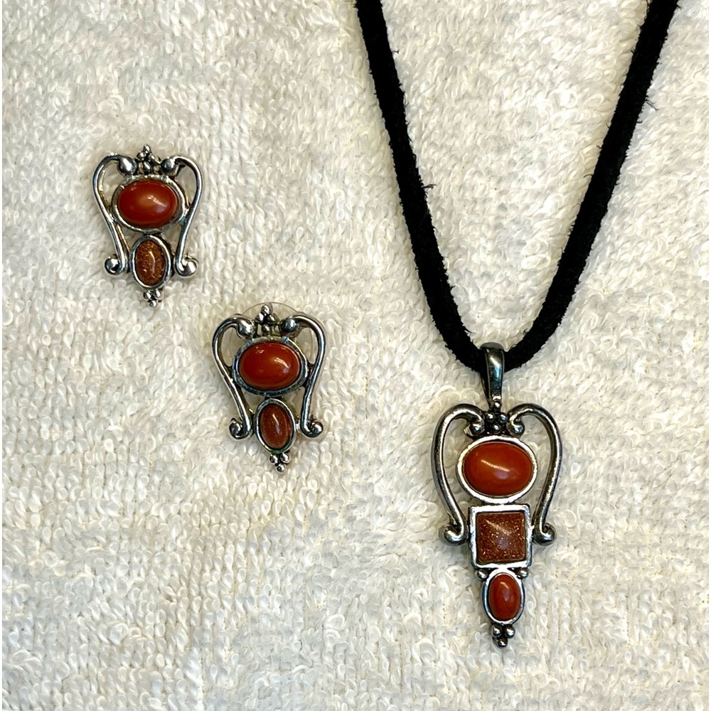 Rust colored stones set in silver with black fabric rope, necklace, and earrings